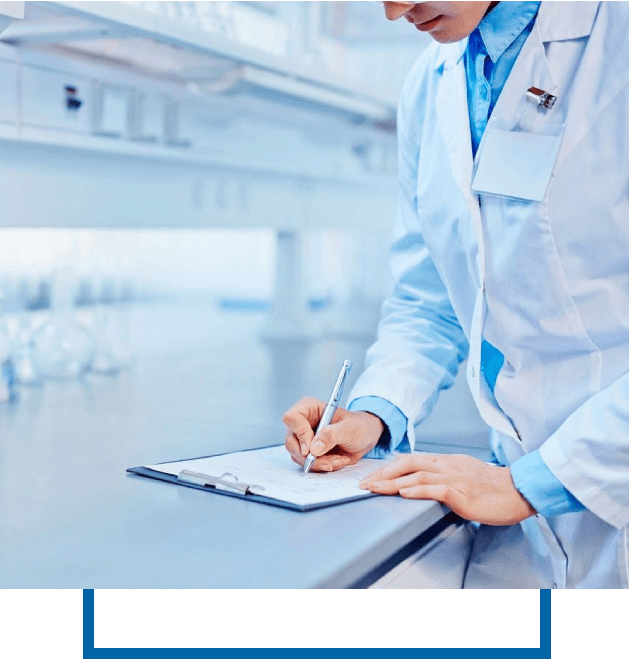 A person in a lab coat writing on a clipboard in a laboratory setting.